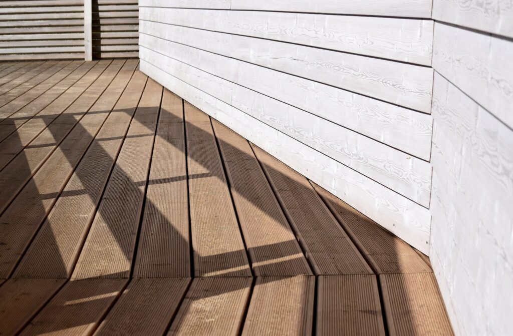 the shadow of a person standing on a wooden deck